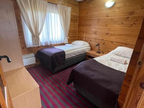Cette chambre comprend 2 lits et une fenêtre. dans l'établissement Domek nad jeziorem Guzowy Piec, à Guzowy Piec