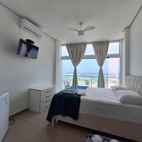 une chambre avec un lit avec vue sur l'océan dans l'établissement Suítes Pitangueiras - POUSADA FRENTE MAR, à Guarujá