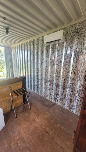 a room with a wall with curtains and a chair at Hospedagem Pé de Serra in Botucatu