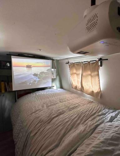 uma cama num pequeno quarto com um ecrã em Delightful 1970's Narrowboat em Londres