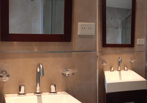 a bathroom with two sinks and two mirrors at DEPARTAMENTO FRANCIA centrico 1 dor in Comodoro Rivadavia