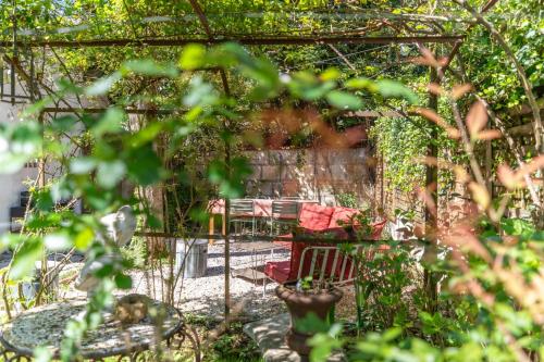 eine Pergola mit einem roten Stuhl in einem Garten in der Unterkunft Maison Marguerite - Welkeys in Bordeaux