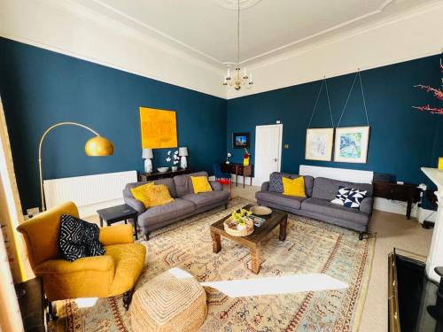a living room with blue walls and yellow furniture at Entire Stylish Colourful Two Bed Flat in Clifton in Bristol