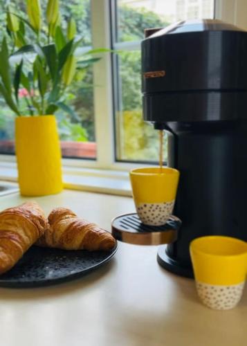 a coffee maker and a plate of croissants on a counter at Entire Stylish Colourful Two Bed Flat in Clifton in Bristol