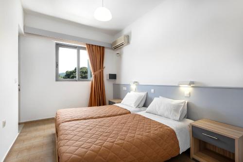 een slaapkamer met 2 bedden en een raam bij Anixis Hotel & Apartments in Ialyssos