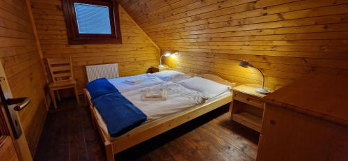 ein kleines Schlafzimmer mit einem Bett in einem Holzzimmer in der Unterkunft Drevenica u Vlada in Hrabušice