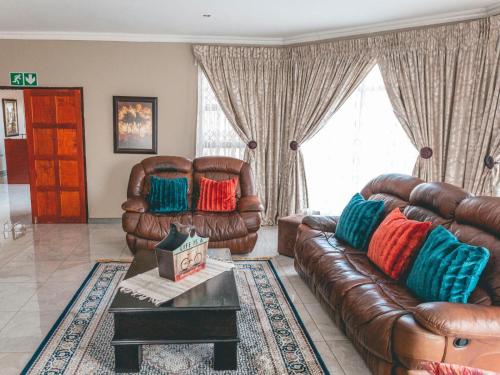 a living room with leather couches and a coffee table at Khutso Boutique Hotel in Hazyview