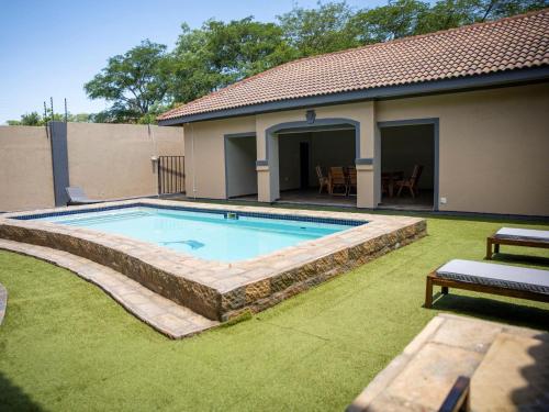 a swimming pool in a yard next to a house at Khutso Boutique Hotel in Hazyview