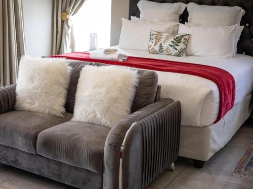 um quarto com uma cama e um sofá com almofadas em Khutso Boutique Hotel em Hazyview