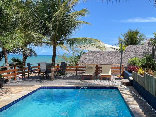 a swimming pool with a table and chairs and the ocean at Arandu Sagi Inn in Baía Formosa