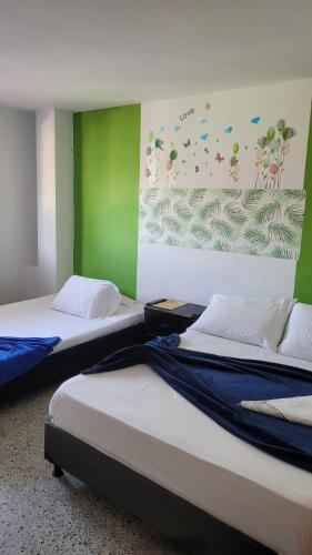 2 camas en una habitación con un cuadro en la pared en Hotel La Avenida, en Guatapé