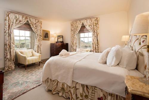 a bedroom with a large white bed and two windows at Broadgate House & Steading in West Woodburn