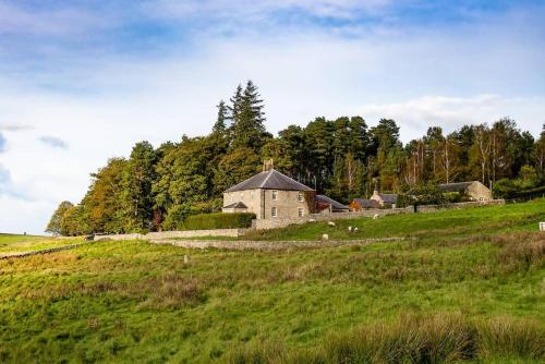 a building on a hill in a green field at Broadgate House & Steading in West Woodburn