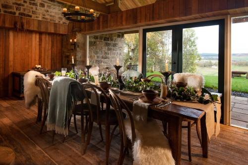 a dining room with a long table and a large window at Broadgate House & Steading in West Woodburn