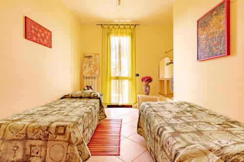 1 dormitorio con 2 camas y ventana en Villa Comi, en Giurdignano