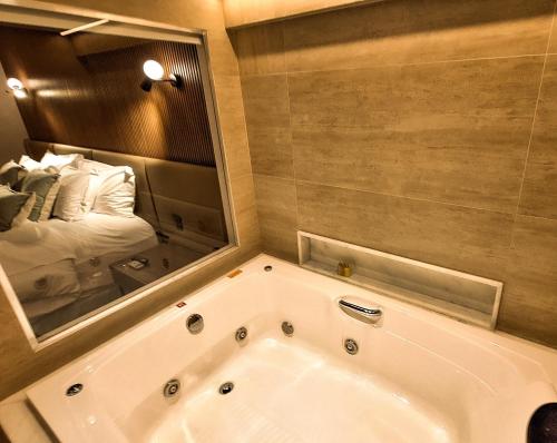 uma banheira na casa de banho com um espelho em Hilton Garden Inn Belo Horizonte Lourdes em Belo Horizonte