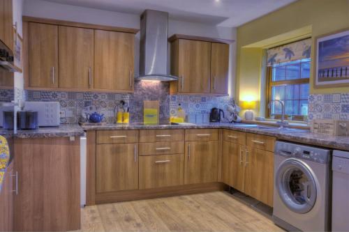 a kitchen with wooden cabinets and a washer and dryer at The Apartment at Allt-Sagart in Golspie