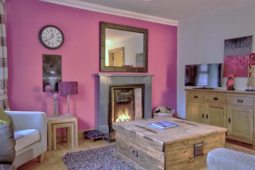 a living room with a pink wall with a fireplace at The Apartment at Allt-Sagart in Golspie