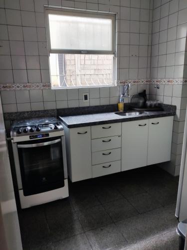 a kitchen with a stove and a sink and a window at Apto com suíte, garagem, localização privilegiada in Belo Horizonte