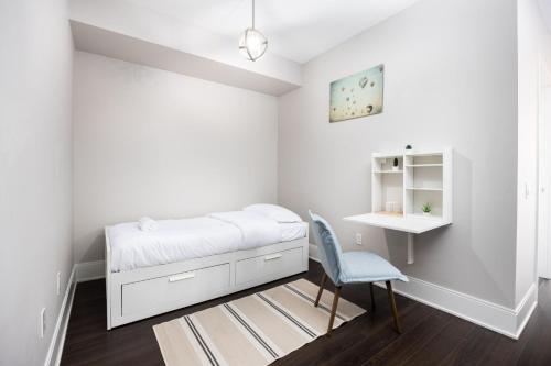 1 dormitorio blanco con 1 cama y 1 silla en DWTN Condo Near CN Tower! w/ Free Parking en Toronto