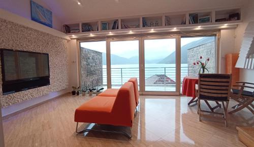 een woonkamer met een bank, een tafel en een televisie bij Sea View Apartment Ljuta in Kotor