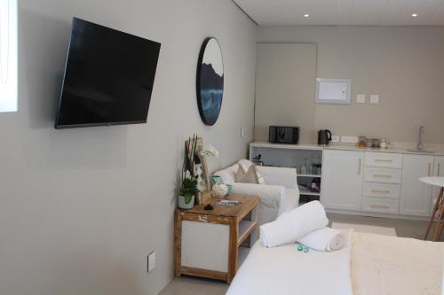 un salon avec un canapé et une télévision sur un mur dans l'établissement Sea Breeze Cottage, au Cap