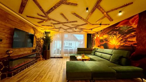 a living room with a green couch and a fireplace at PARADiSE Wellness Residence - Sauna&SPA in Terchová
