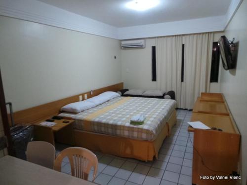 um quarto de hotel com uma cama, uma mesa e cadeiras em Flat Mobiliado em João Pessoa