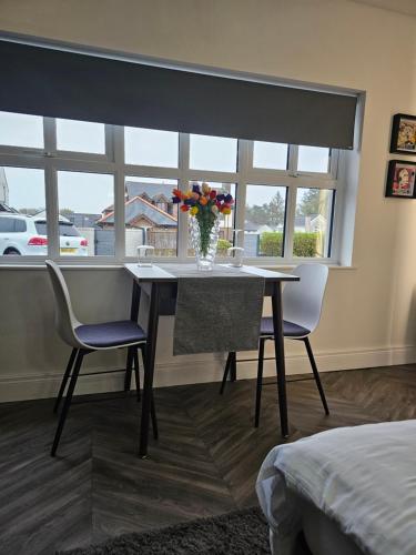 a dining room table with two chairs and a vase of flowers at Home Sweet Home in Ballycastle