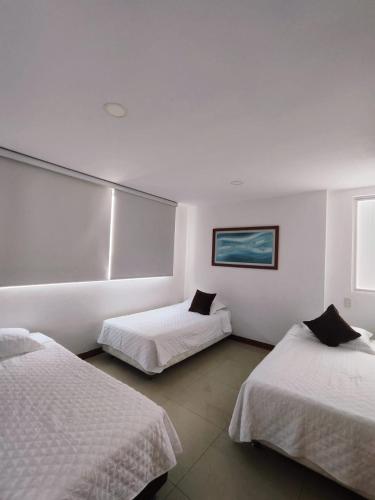 a hotel room with two beds with white sheets at Palmetto 2HABS vista de frente al mar. in Cartagena de Indias