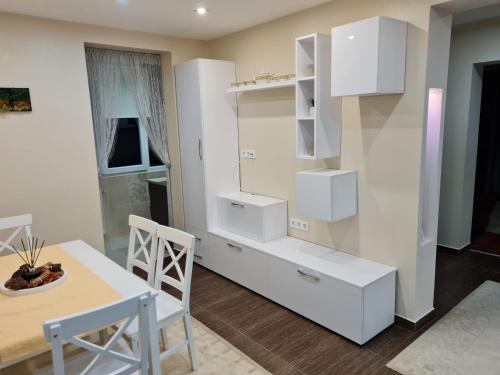 eine Küche mit weißen Schränken, einem Tisch und einem Esszimmer in der Unterkunft Luxury Large Family Apartment in Zalău