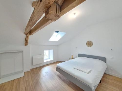 a white bedroom with a bed and a wooden floor at Moscou, Grande Maison proche Reims in Berru