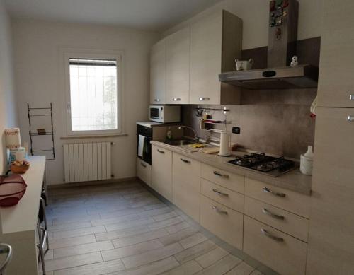a large kitchen with white cabinets and a window at Villa Maria in Marina di Ravenna