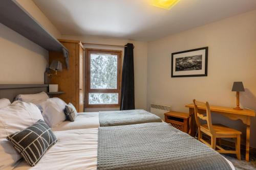 une chambre avec deux lits et un bureau et une fenêtre dans l'établissement Résidence Les Arcs 1950 Le Village - maeva Home - Appartement 3 pièces 6 personnes - Exclusive MAE-0145, à Bourg-Saint-Maurice