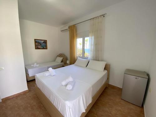 a bedroom with a large white bed and a window at Yard Paradise in Dhërmi