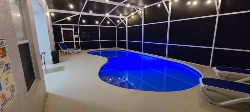 een groot blauw zwembad in een kamer met zwarte tegels bij Home Close to Disney Parks/Amazing Private Pool in Orlando