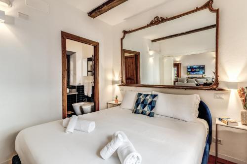 a bedroom with a white bed with a large mirror at MAYA RHOME TRASTEVERE in Rome