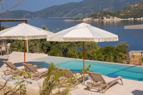 a pool with chairs and umbrellas next to a lake at Villa Armiriki-Private Sea Access in Évyiros