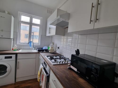 a kitchen with a stove and a microwave at London Zone 2, Easy Travel in London