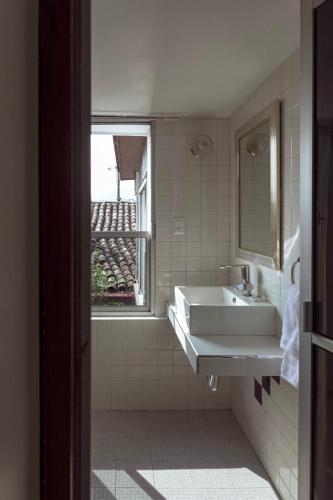 a white bathroom with a sink and a window at Posada Galeria Alberto Sedas in Huatusco de Chicuellar