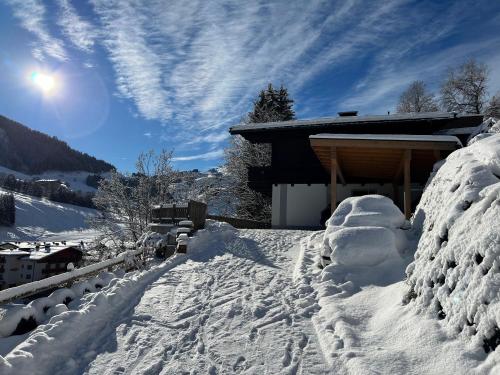 a house covered in snow next to a building at Chalet Apartments Ferius inklusive Jokercard im Sommer in Saalbach Hinterglemm