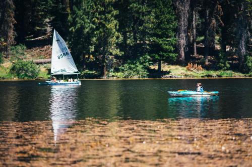 two people in boats on a lake with a sail boat at Montecito Sequoia Lodge in Sequoia National Park
