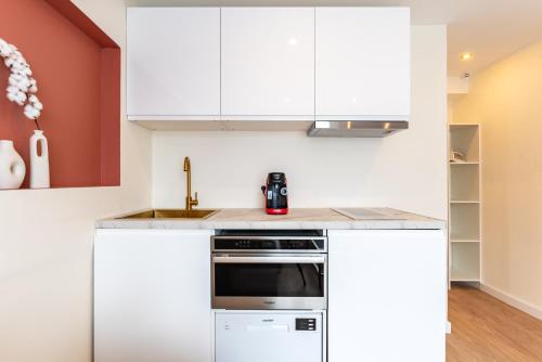 a kitchen with white cabinets and a stove at Studios Le Médicis in Rouen