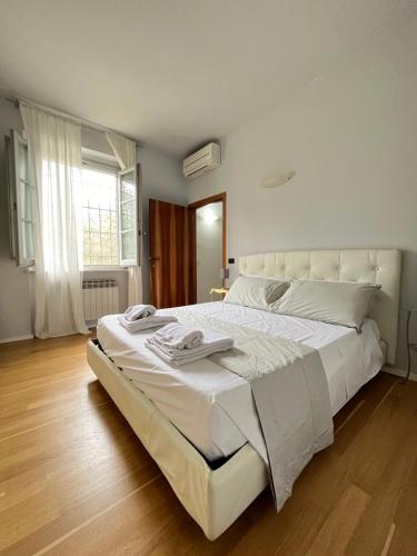 uma grande cama branca num quarto com pisos em madeira em Villa Mary, relax nel cuore del Chianti em Poggibonsi