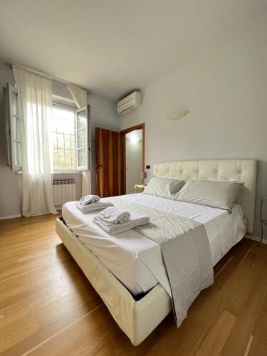 a large white bed in a bedroom with wooden floors at Villa Mary, relax with swimming pool in Poggibonsi