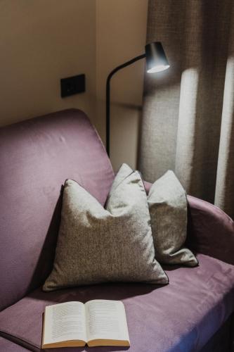 a book on a bed with pillows and a lamp at TANOVINUM Apartments in Villandro