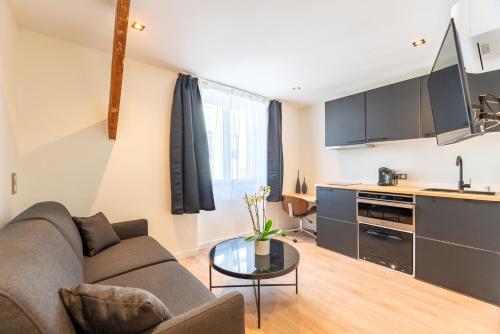 a living room with a couch and a table at Studios Le Médicis in Rouen