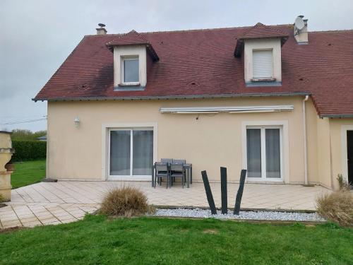 Cette maison dispose d'une terrasse avec une table dans la cour. dans l'établissement Au bon repos, à Maisons
