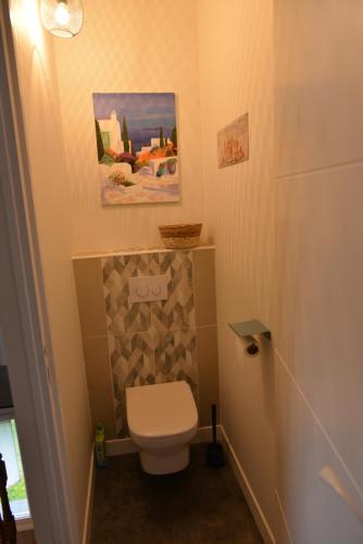 a bathroom with a toilet and a painting on the wall at Villa Cap Avalenn in Fouesnant