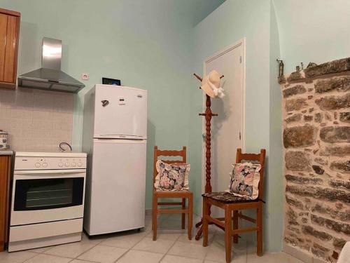 a kitchen with a white refrigerator and two chairs at Traditional stone house in Pyrgi in Chios
